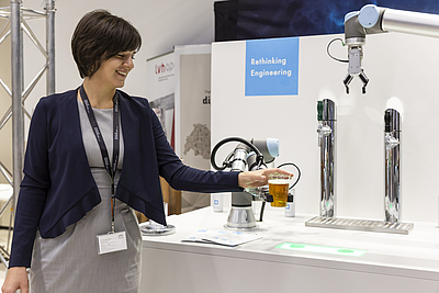 Mehr als 20 Aussteller zeigten neueste Innovationen im Bereich Automatisierung/Digitalisierung. Frau stehend mit Bierglas in der Hand, aus Maschine kommt Bier