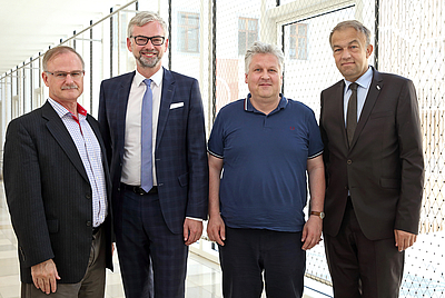 Vier Männer stehen nebeneinander und blicken in die Kamera