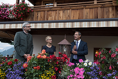 Es stehen drei Personen am Balkon des Gasthauses Roßmoos.