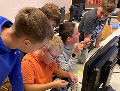 Mehrere Kinder vor einem PC in einem Klassenraum der MMS Neufelden